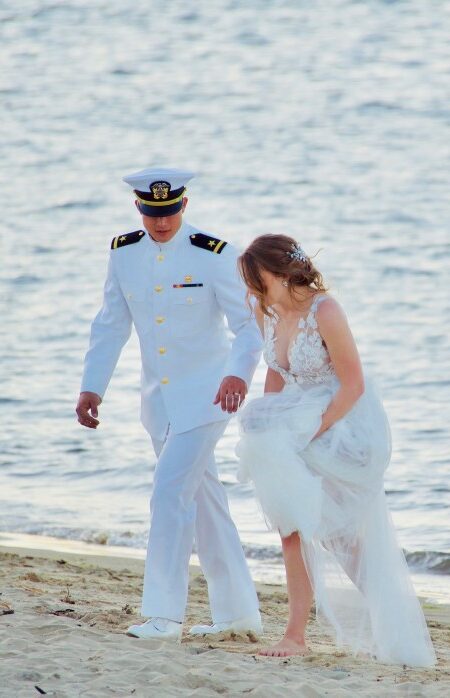 beautiful-scene-of-a-navy-man-in-uniform-walking-with-his-bride-on-the-sand-by-the-seashore_t20_bxNXXm